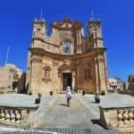 A young female tourist roaming around Gozo. A Roman Catholic Church in Gharb, Gozo Malta.